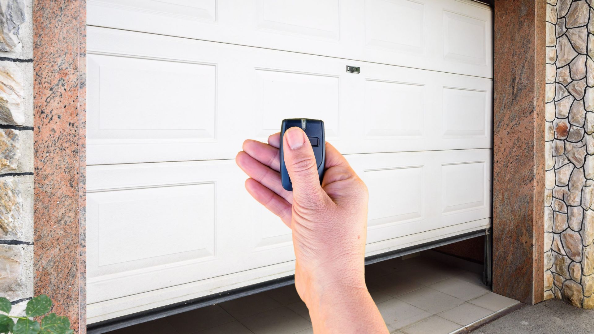 A person operating an automatic garage door with a remote.